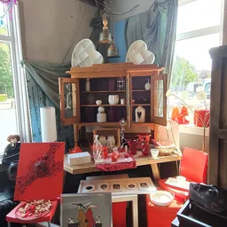 Vintage houten vitrinekast met deuren en glas, uitgestald met decoratieve items en rode accessoires