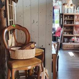 Houten stoelen en meubels met rieten mand en decoratieve items in kringloopwinkel
