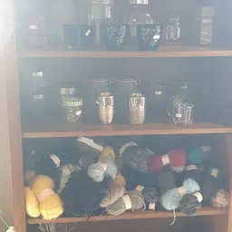 Kastplank met glazen containers, kannen en huishoudelijke spullen in donker licht.