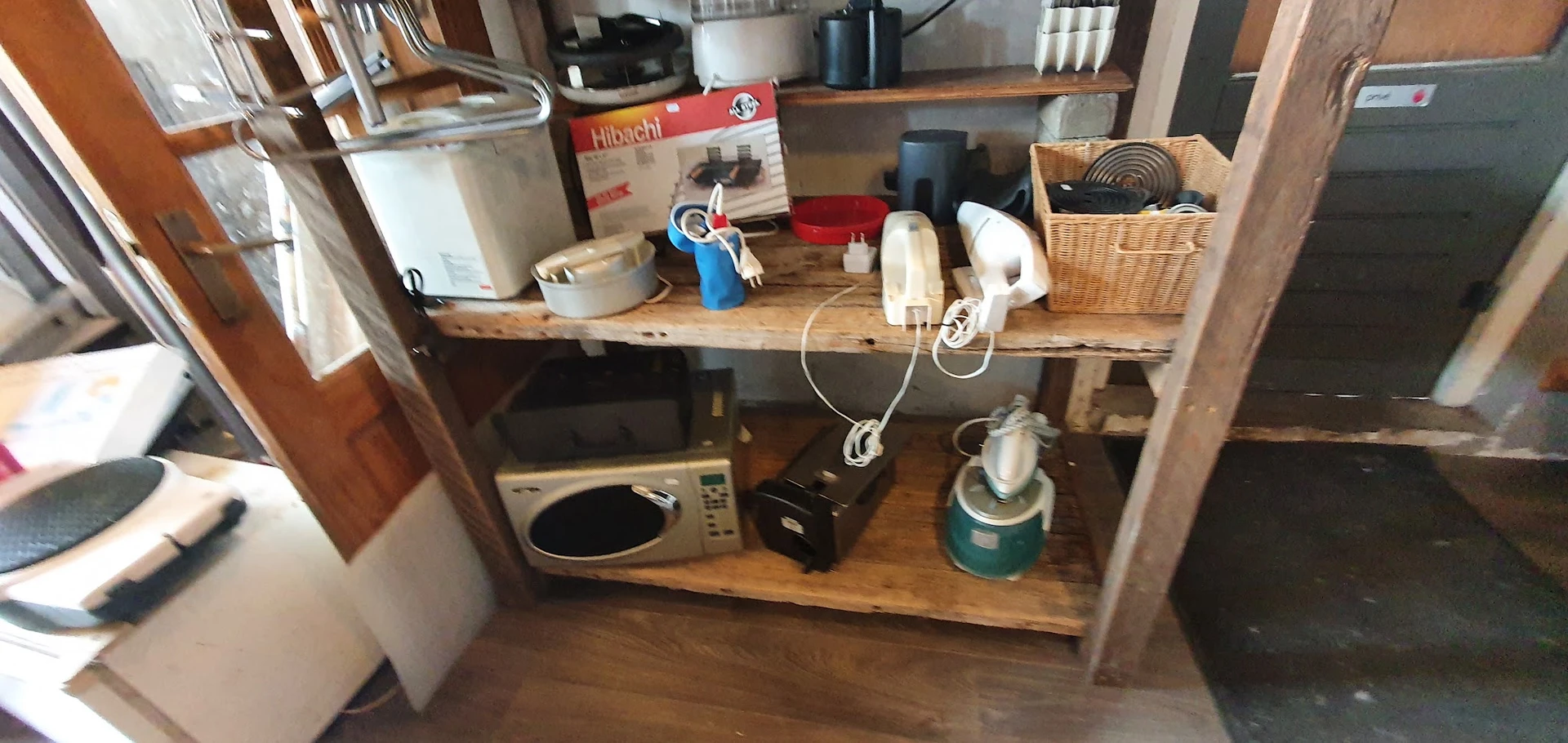 Houten stellingen met huishoudelijke artikelen en keukengerei in verschillende vakken.