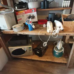 Houten stellingen met huishoudelijke artikelen en keukengerei in verschillende vakken.