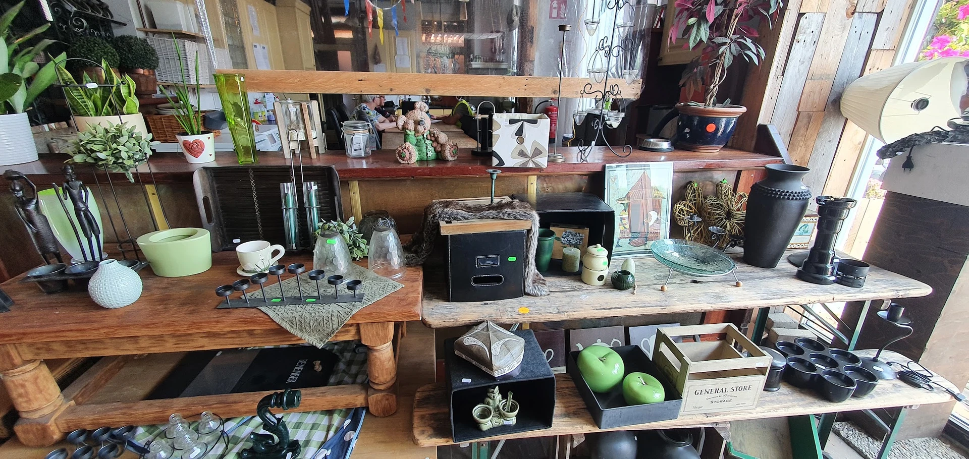 Werkplek in een kringloopwinkel met houten tafels, verschillende spullen, huishoudapparatuur en decoratieve items