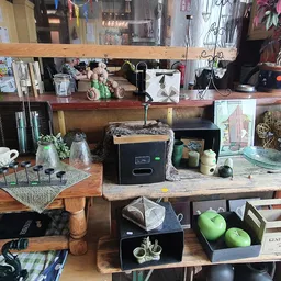 Werkplek in een kringloopwinkel met houten tafels, verschillende spullen, huishoudapparatuur en decoratieve items