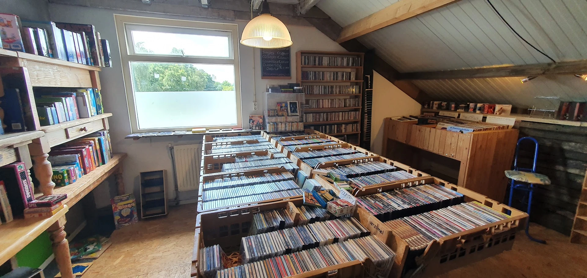 Grote collectie cd's en dvd's uitgestald in houten bakken op de vloer van de winkel