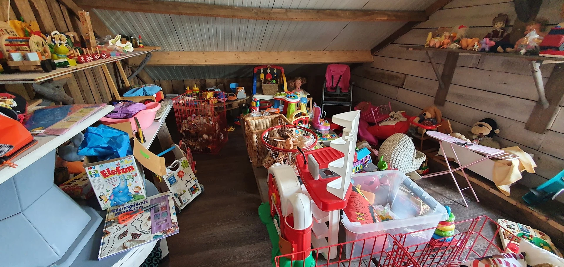 Overzicht van een volgeladen opslagruimte met dozen, speelgoed, kleding en huishoudartikelen