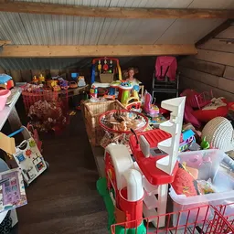 Overzicht van een volgeladen opslagruimte met dozen, speelgoed, kleding en huishoudartikelen