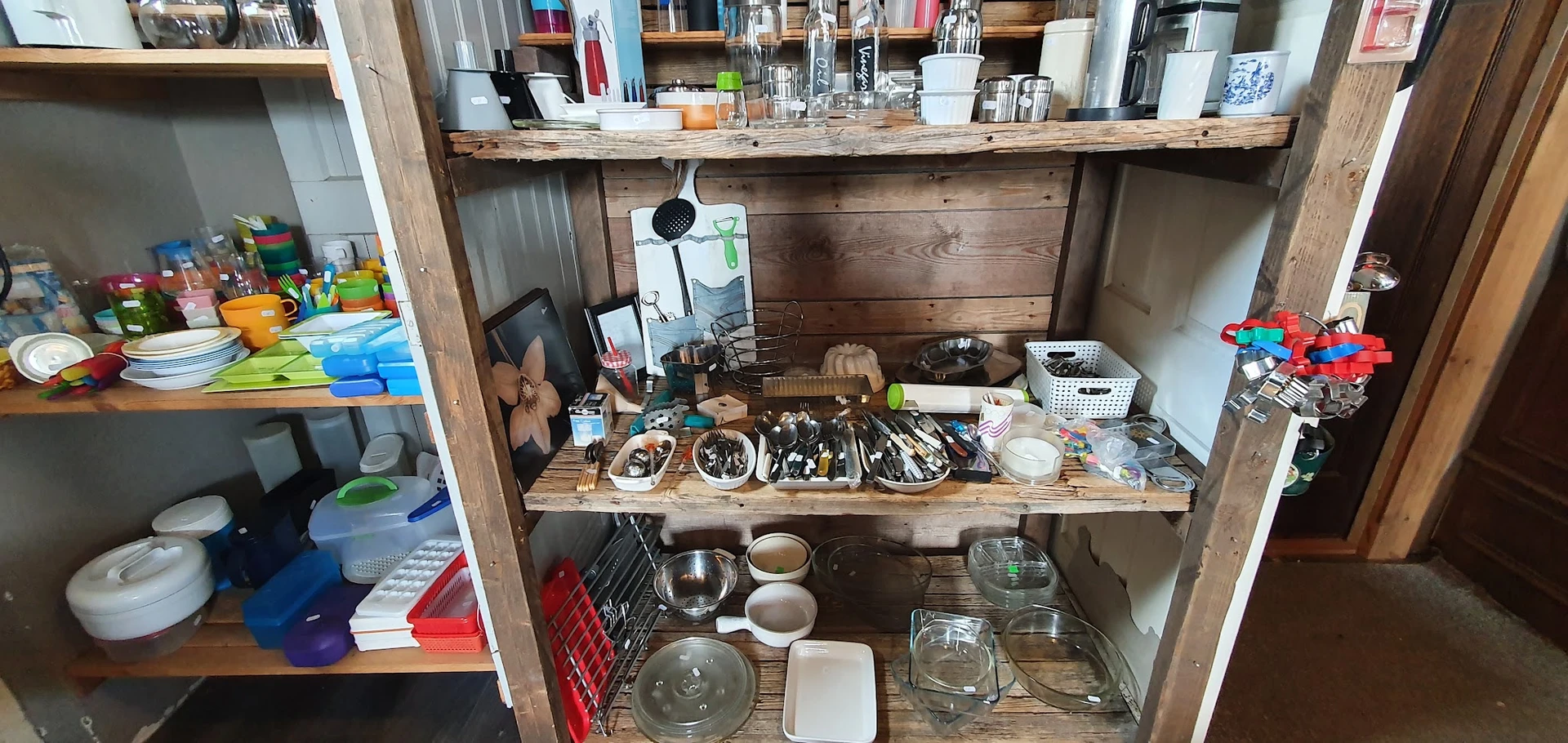 Houten kast met servies, bestek, glazen en keukenspullen uitgestald op meerdere planken