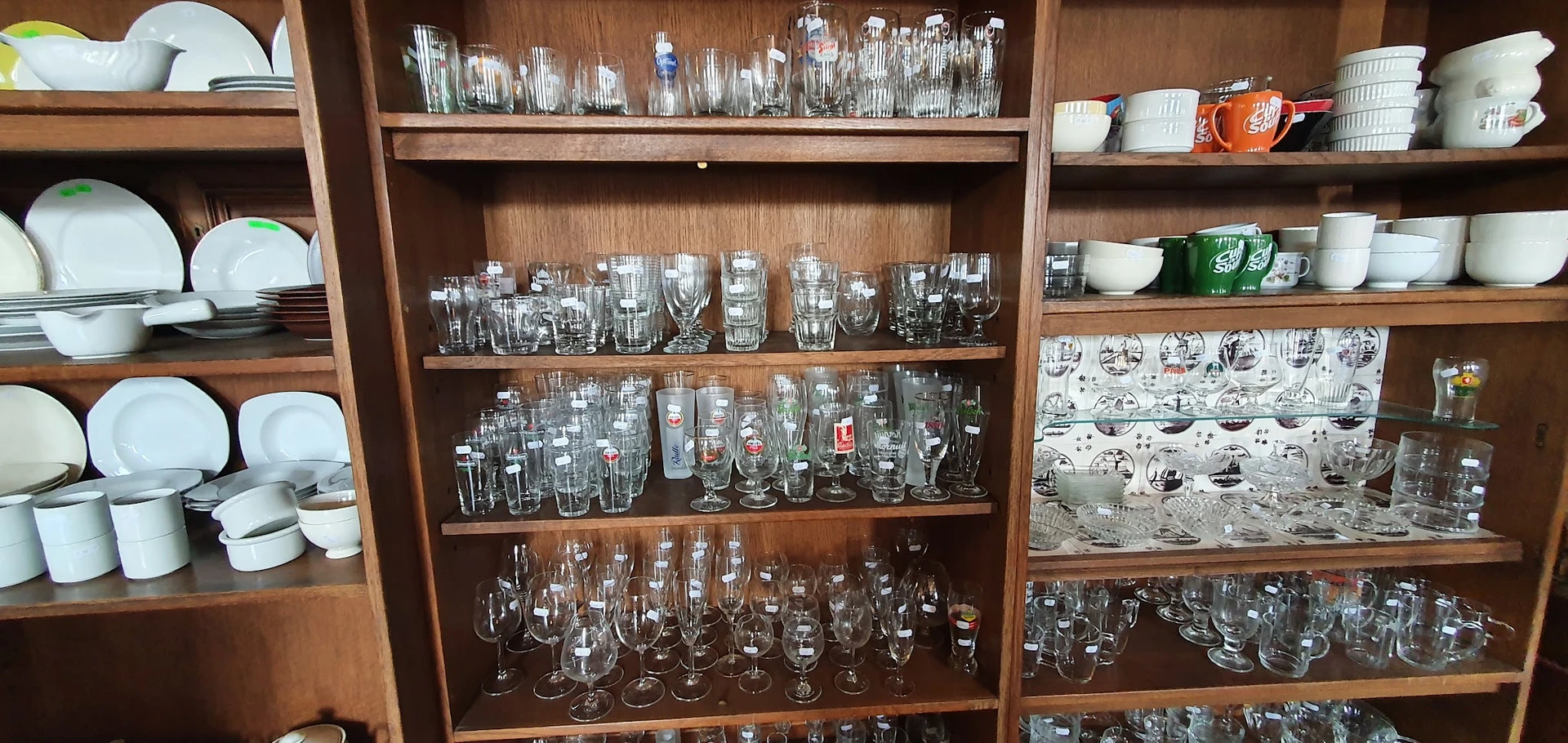 Houten vitrinekast gevuld met glazen en drinkglazen van verschillende vormen en maten