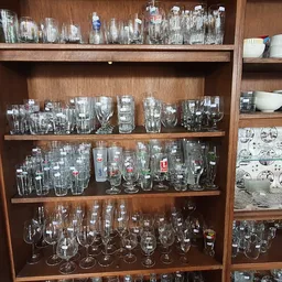 Houten vitrinekast gevuld met glazen en drinkglazen van verschillende vormen en maten