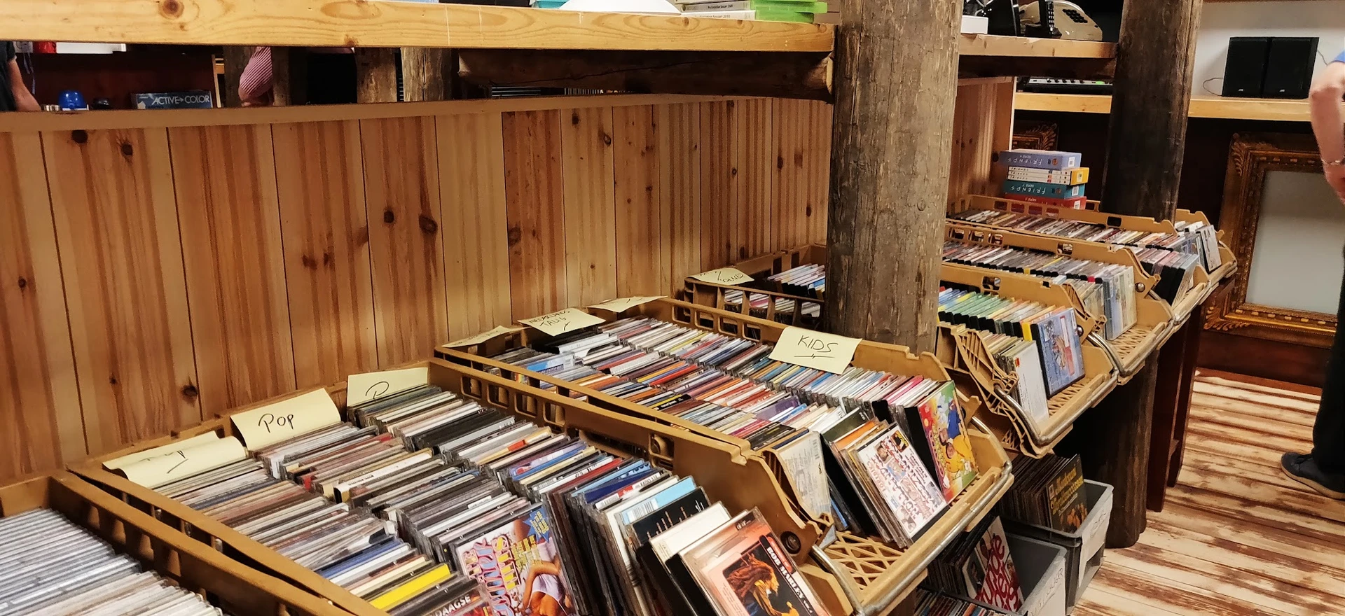 Houten bakken en dozen met uitgestalde cd's en dvd's in een kringloopwinkel