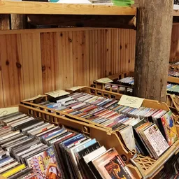 Houten bakken en dozen met uitgestalde cd's en dvd's in een kringloopwinkel