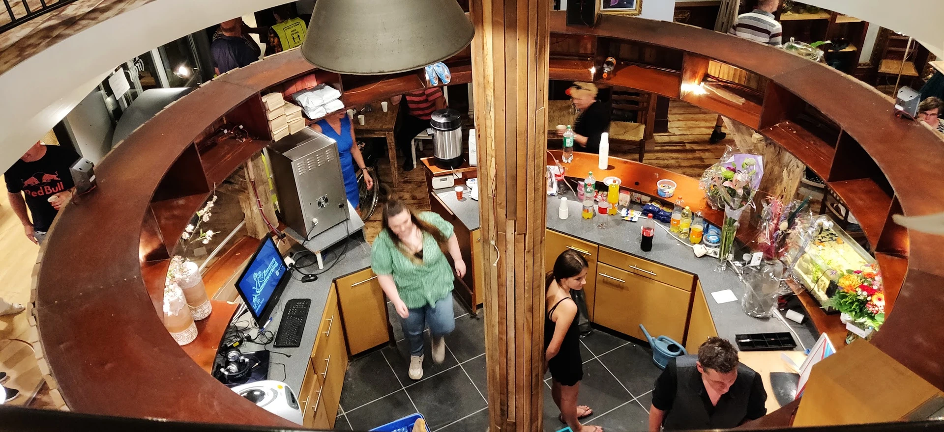 Overzicht van de binnenkant van een kringloopwinkel met bezoekers, kasten, toonbank en diverse spullen