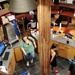 Overzicht van de binnenkant van een kringloopwinkel met bezoekers, kasten, toonbank en diverse spullen