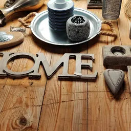 Huishoudelijke decoratieartikelen en speelgoed uitgestald op houten tafel, waaronder het woord HOME en diverse keukengereedsc
