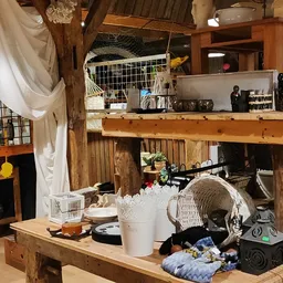 Houten stellingen en tafels vol met tweedehands spullen, huishoudartikelen en textiel in een kringloopwinkel