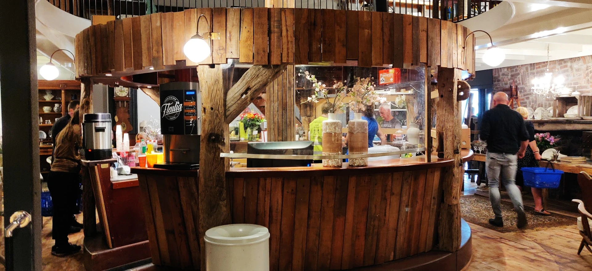 Koffiehoek met houten bar, koffiemachine en display met bloemen in kringloopwinkel