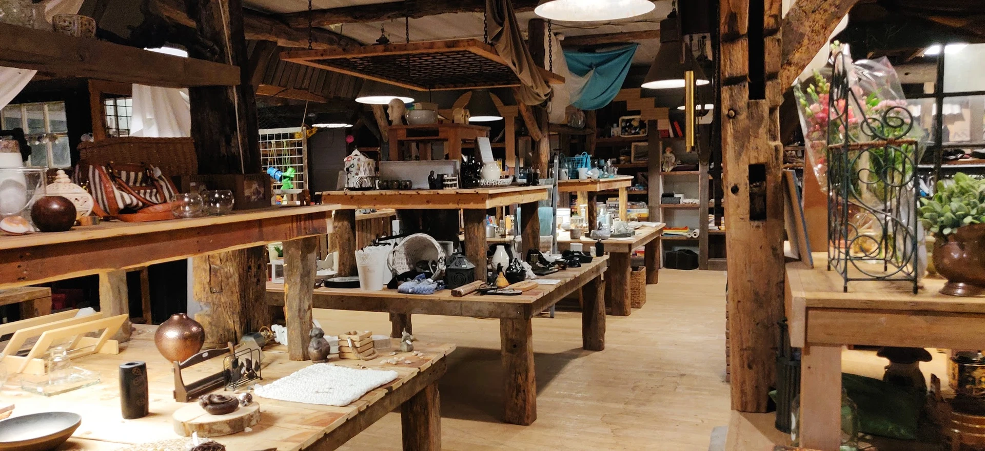 Ruim winkelbinnenland met houten tafels, stellingen met spullen en hangende decoratie