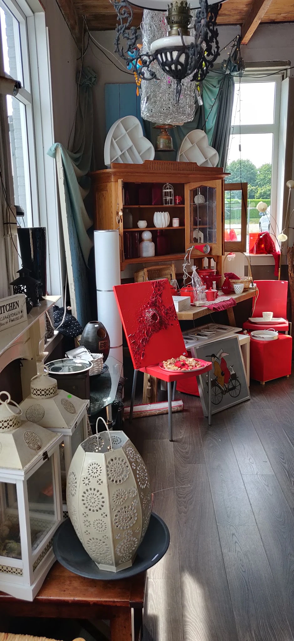 Winkelvloer met rode meubels, houten kasten, servies en huishoudartikelen uitgestald