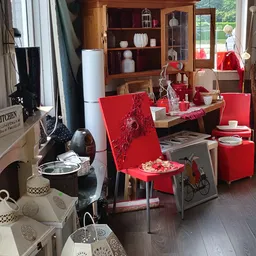 Winkelvloer met rode meubels, houten kasten, servies en huishoudartikelen uitgestald