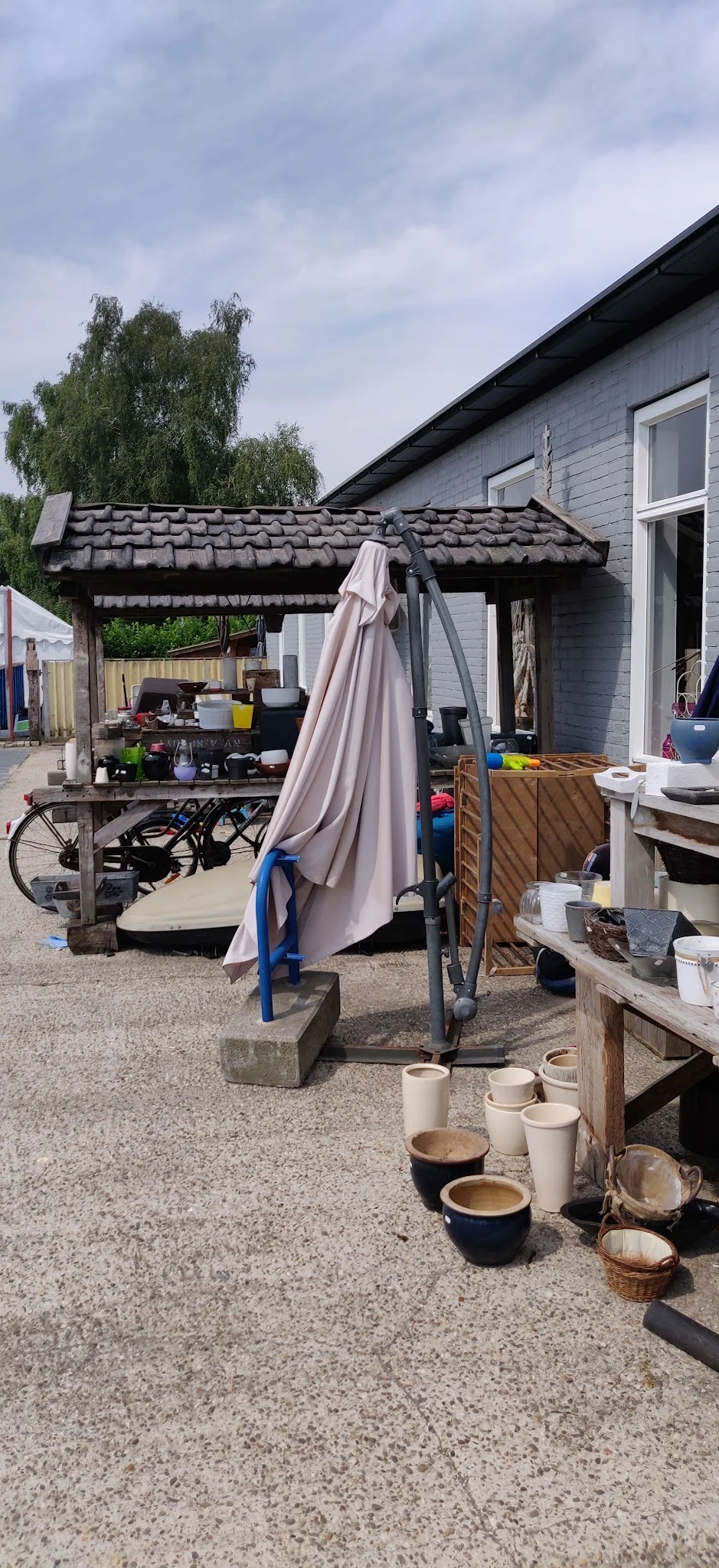 Buitenterrein met parasol, fiets, diverse spullen en houten schuur
