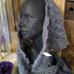 Zwart hoofd met goudkleurige oorbellen, gehuld in grijze haakwerkstof