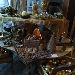 Kerstdecoratie en versieringen uitgestald op tafels, met gouden en zilveren ballen, takken in vazen en feestelijke ornamenten