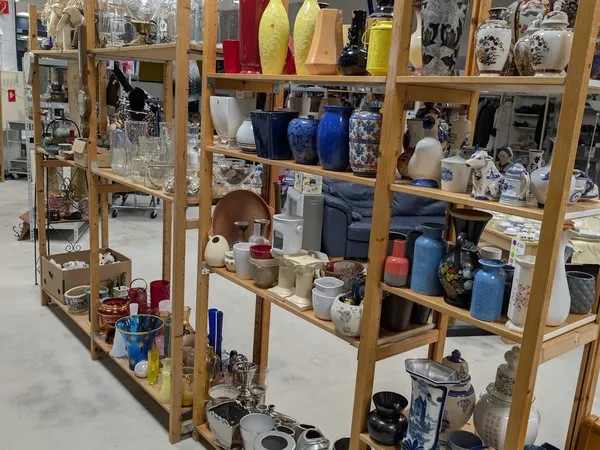 Houten stellingkasten gevuld met diverse huishoudelijke artikelen en serviesgoed in verschillende kleuren
