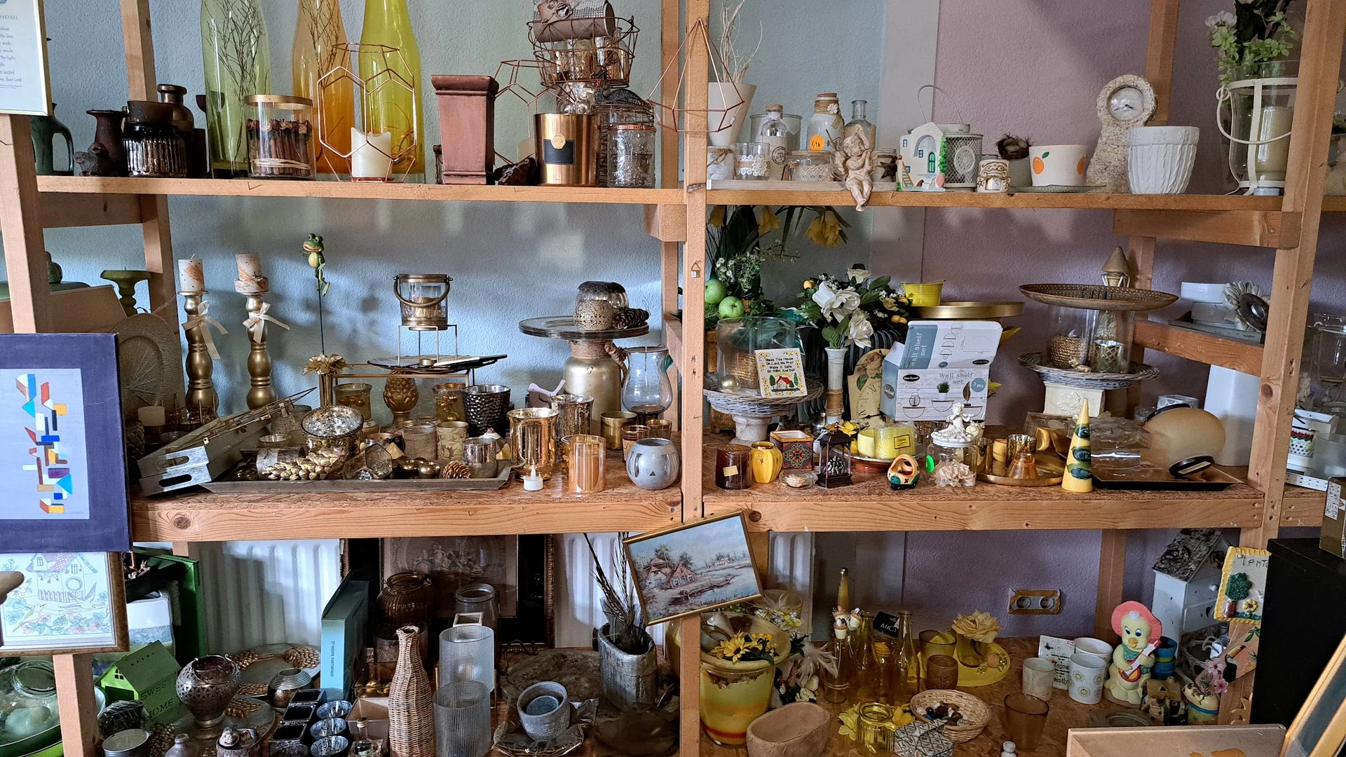 Houten stellingen volgesteld met diverse huishoudelijke artikelen, kandelaars, flessen, serviesgoed en decoratieve voorwerpen
