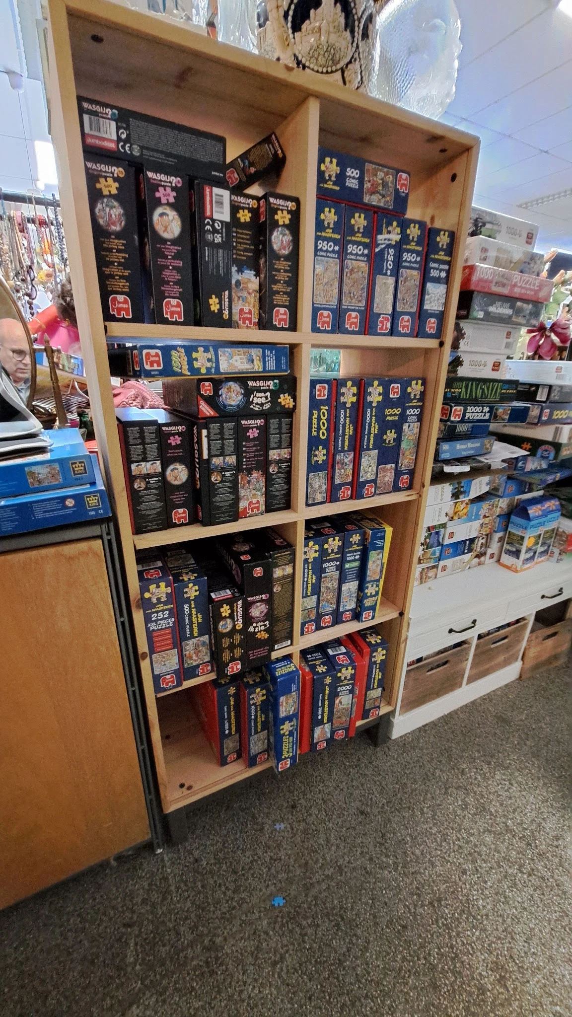 Houten stellingkast met uitgestalde puzzels en bordspellen in doosjes