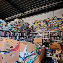 Magazijnruimte met hoge stellingen vol boeken, dvd's en dozen in een kringloopwinkel