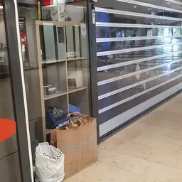 Winkelbinnenkant met glazen kastje en verlichte schappen, kartonnen dozen met spullen op de vloer