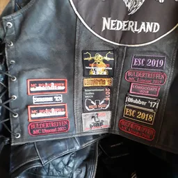Zwart leren motorjack met patches en emblemen van motorclubevenementen