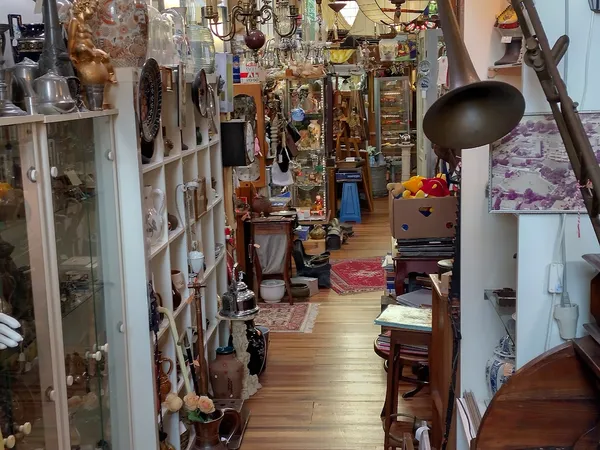 Smal gangpad in een brocantezaak vol met antieke voorwerpen, lampen, meubels en decoratie aan beide zijden