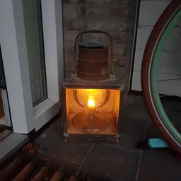 Oranje glazen lantaarn met brandend licht, staand op donkere ondergrond