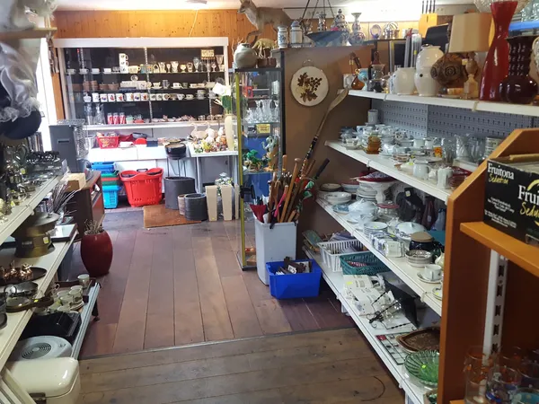 Winkelinterieur met stellingen, rekken en vitrines vol tweedehandsartikelen, kunstnijverheid en huishoudelijke spullen