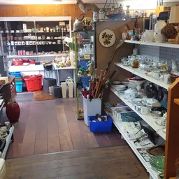 Winkelinterieur met stellingen, rekken en vitrines vol tweedehandsartikelen, kunstnijverheid en huishoudelijke spullen