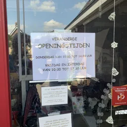 Wit papier op winkelruit met gewijzigde openingstijden in Nederlands