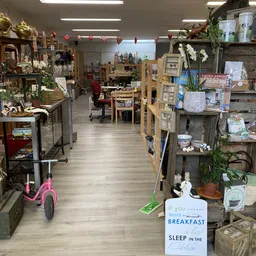 Overzicht van een kringloopwinkel met houten vloer, stellingen met diverse spullen, decoraties en een breakfast-bord rechtsvo
