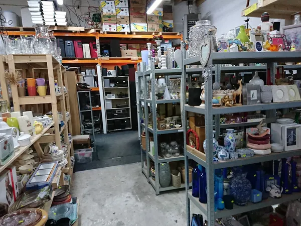Winkelvloer met stellingen vol huishoudartikelen, servies, glazen en decoratieve spullen in een kringloopwinkel