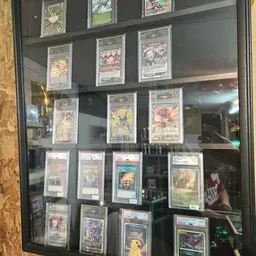Vitrinekast met ingelijste verzamelkaarten achter glas, mogelijk Pokémon of trading cards