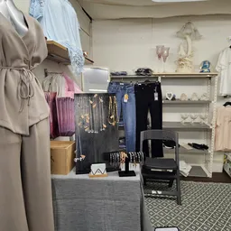 Winkelinterieur met uitgestalde kleding, accessoires en sieraden op stellingen en mannequins