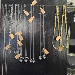 Uitgestalde sieraden op een zwart displaybord, waaronder kettingen en armbanden met goudkleurige accenten