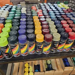 Uitgestalde spuitbussen in verschillende kleuren, gerangschikt in rijen op een tafel