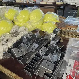 Tafel met gele emmers in plastic, kartonnen dozen en zwarte kunststof bakken met dividers