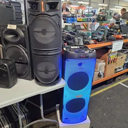 Uitgestalde audio- en muziekapparatuur: luidsprekers, een blauwe subwoofer en andere elektronische apparaten in een kringloop