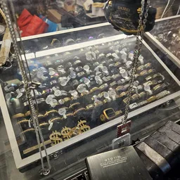 Vitrinekast met zilverwerk, sieraden en kettingen uitgestald op zwart fluweelachtig materiaal