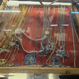 Vitrinekast met zilveren en gouden kettingen en hangers op rode achtergrond