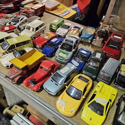 Verzameling speelgoedauto's en miniatuurauto's uitgestald op een witte tafel
