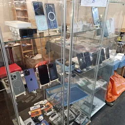 Vitrinekasten met tweedehands elektronicaartikelen: smartphones, speakers en accessoires