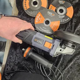 Haakse slijper met oranje en grijze kleurstelling, in hand gehouden naast slijpschijven